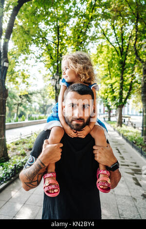 Petite fille à cheval sur les papas cou Banque D'Images