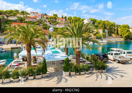 Palmiers et de tables de restaurant dans le magnifique port de Supetar, sur l''île de Brac, Croatie Banque D'Images