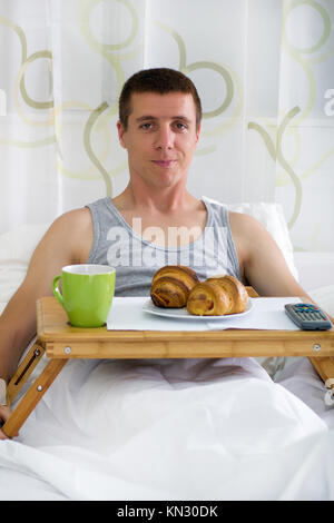 Photo d'un homme ayant le petit déjeuner dans le lit Banque D'Images