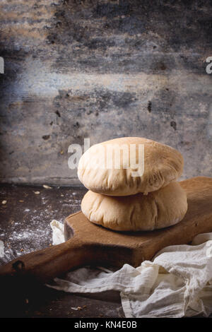 Deux de farine de pain de pita sur planche à découper en bois, servi avec de la farine sur la table sombre Banque D'Images