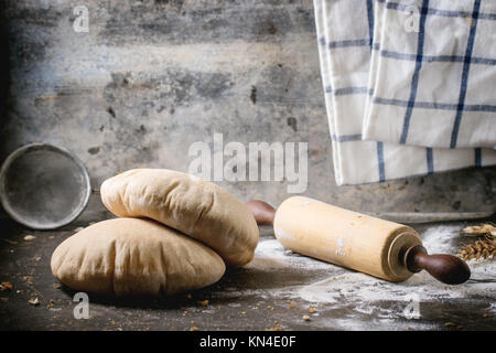 Deux de farine de pain de pita sur planche à découper en bois, servi avec du matériel roulant vintage broches et la farine sur la table sombre Banque D'Images
