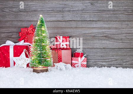 Cadeaux rouge et petit arbre de Noël avec des lumières de Noël sur fond de bois rustique Banque D'Images