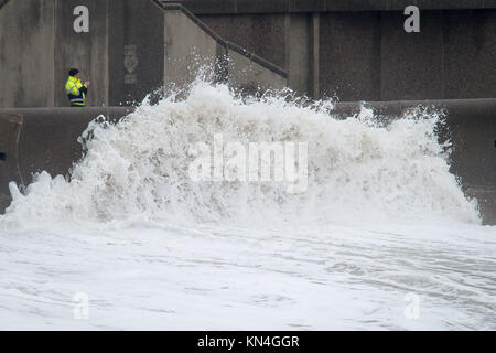 Correction retransmis dans le byline de légende. Un homme photographies vagues sur la promenade mur à Porthcawl, Galles du Sud, comme les fortes chutes de neige dans certaines parties de l'UK est à l'origine des troubles, la fermeture de routes et de vols de mise à la terre dans un aéroport. Banque D'Images