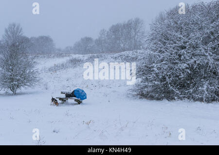 Banc en bois chaise dans un parc couvrir complètement avec de la neige après une tempête de neige pendant l'hiver, vacances de Noël, un sac à dos, parapluie, Sac trépied de l'appareil photo et un petit sac sur la chaise. Banque D'Images