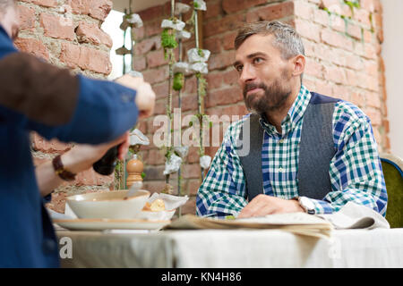 Portrait of smiling barbu assis à table cafe enjoying meal et parler à tes collègues pendant les temps de déjeuner, copy space Banque D'Images