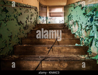 Escalier abandonné avec la peinture pèle. Intérieur d'une usine abandonnée. Ancien ruban vidéo ruiner si le centre de l'escalier Banque D'Images