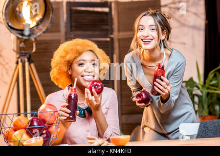 Les femmes avec des fruits et des smoothies à la maison Banque D'Images