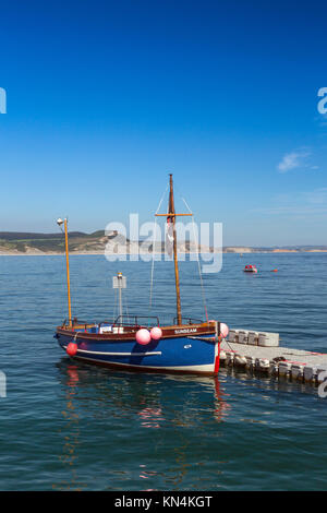 Un petit moteur bateau amarré en face de Golden Cap à Lyme Regis sur la côte jurassique Site du patrimoine mondial, Dorset, England, UK Banque D'Images