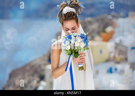 Belle femme en robe blanche avec mariage bouquet sur fond de la mer et l'île de Santorin Banque D'Images