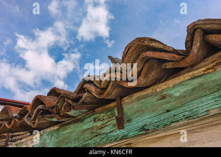 Toit en bois vintage avec des tuiles rouges et eaves détail sous un ciel bleu avec des nuages blancs moelleux Banque D'Images