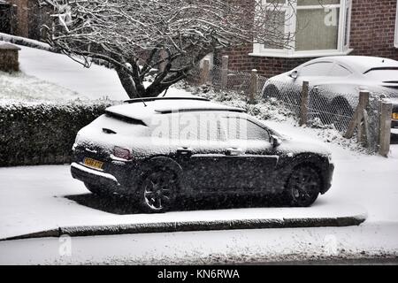 Une voiture garée sur le côté de la route avec descendre mince couche de neige. Banque D'Images