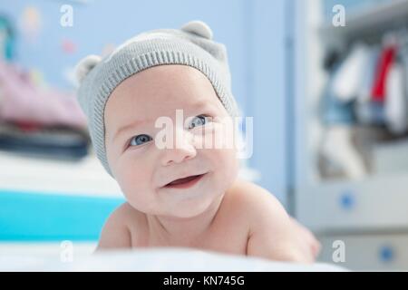 Portrait d'un bébé de quatre mois en souriant. Il est face vers le bas.