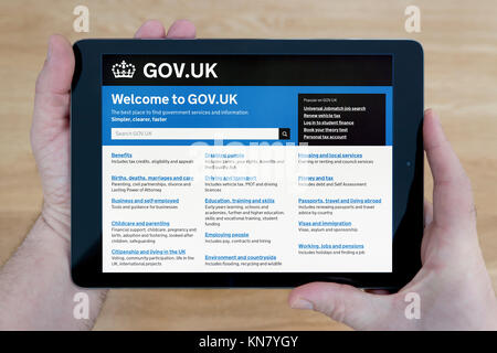 Un homme regarde le Gov.UK site sur son iPad tablet device, tourné contre une table en bois page contexte (usage éditorial uniquement) Banque D'Images