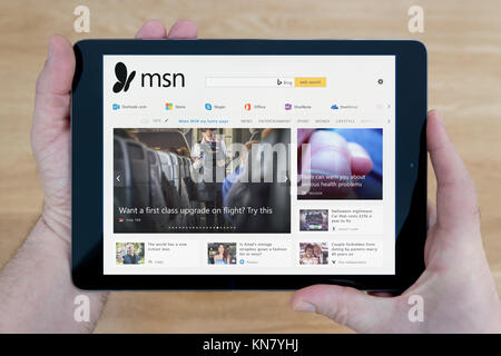 Un homme se penche sur le site Web MSN sur son iPad tablet device, tourné contre une table en bois page contexte (usage éditorial uniquement) Banque D'Images