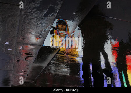 La pluie de Londres - un modèle dans un manteau imperméable reflétée sur une chaussée mouillée à Piccadilly Circus Banque D'Images