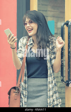 Belle jeune femme asiatique à la recherche de téléphone intelligent avec bonheur l'émotion Banque D'Images