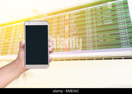 La main féminine useing téléphone mobile contre Conseil d'information de vol , travel concept Banque D'Images