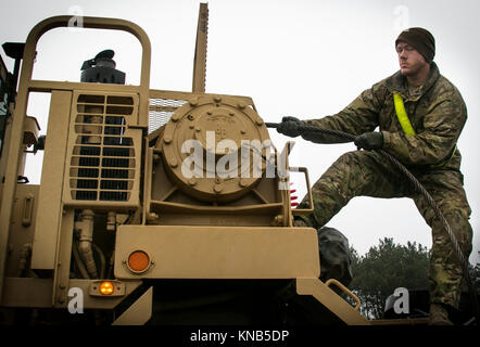 La CPS. Tyrel Denton, un chauffeur de camion militaire affecté à la 32e Compagnie de composite, 68e Bataillon de soutien de soutien au combat, 4e brigade de maintien en puissance, 4e Division d'infanterie, se déroule un câble sur un système de transport d'équipement lourd (HETS) sur commande pour remorquer un autre véhicule à un aérodrome près de Pozwidz, Pologne, 5 décembre 2017. Denton, un Rushville, Neb. native, et les autres soldats américains dans son unité font partie d'un déploiement de neuf mois en Pologne. (U.S. Army Banque D'Images