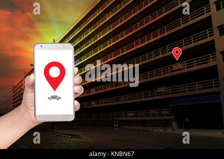 'Car Finder' main femelle useing parking téléphone mobile contre l'arrière-plan de construction Banque D'Images