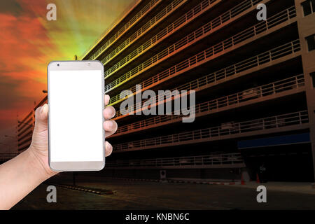 La main féminine useing parking téléphone mobile contre l'arrière-plan de construction Banque D'Images