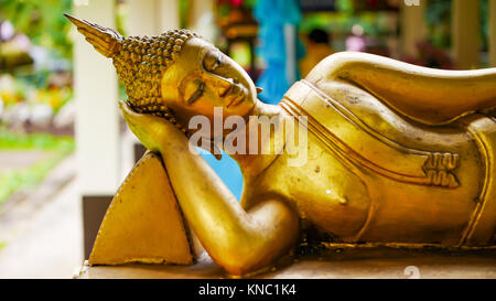 Golden bouddha couché libre , mettre la tête sur un oreiller de triangle. Mettre une main sur les hanches , et l'autre bras sous la tête. Banque D'Images