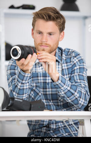 Jeune homme contrôle objectif de son appareil photo Banque D'Images