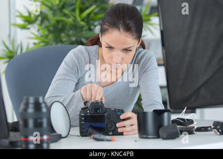 Femme photographe démontage photo caméra sur le lieu de travail Banque D'Images