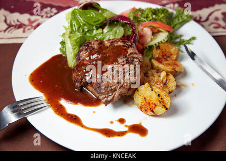 Faux filet de boeuf grillé steak avec les quartiers de pommes de terre et salade verte servi dans un warung local (petit restaurant). Bali, Indonésie. Banque D'Images