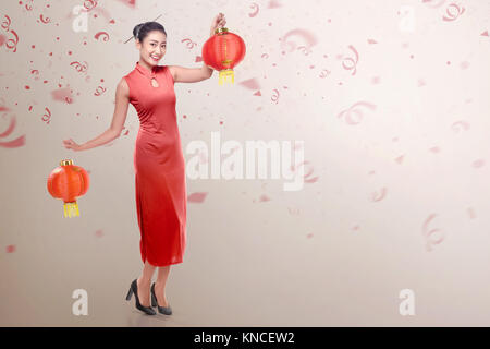 Jeune femme chinoise portant robe cheongsam holding lampe chinoise. Joyeux Nouvel An chinois Banque D'Images