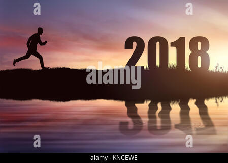 Silhouette of woman running atteindre objectif de 2018 au coucher du soleil. Bonne Année 2018 Banque D'Images