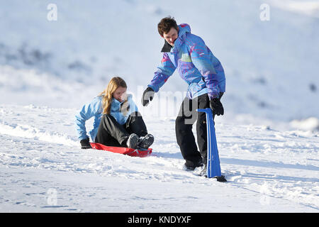 Sur la photo : un jeune homme et une femme sur des traîneaux à l'histoire des armes dans les Brecon Beacons, Pays de Galles, Royaume-Uni. Lundi 11 décembre 2017 Re : des températures de gel, neige Banque D'Images