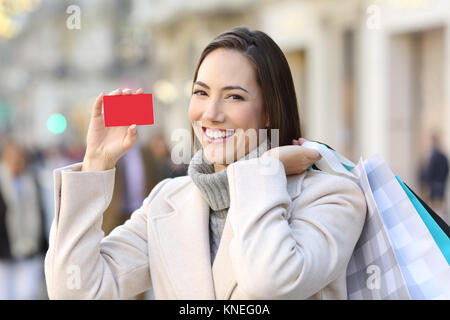 Portrait d'un client heureux montrant une carte de crédit en blanc dans la rue en hiver Banque D'Images