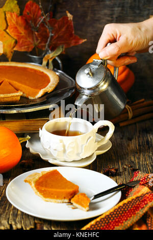 Woman pouring une tasse de thé et une tranche de tarte à la citrouille Banque D'Images