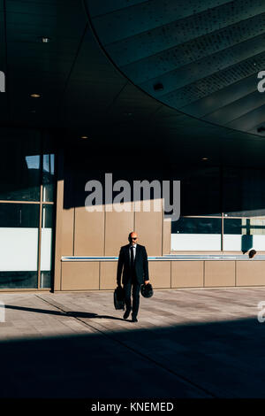 Mature businessman walking outdoors, sac de transport et de casque de moto, vue avant Banque D'Images