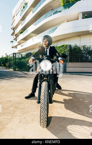 Portrait of businessman outdoors, assis sur la moto, le port de casque de moto Banque D'Images