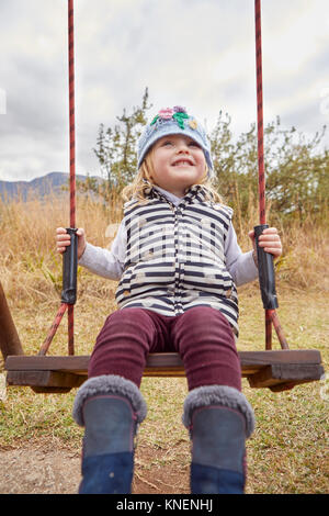 Girl sitting on swing en milieu rural Banque D'Images
