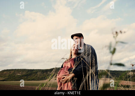 Portrait of happy pregnant couple dans les champs Banque D'Images