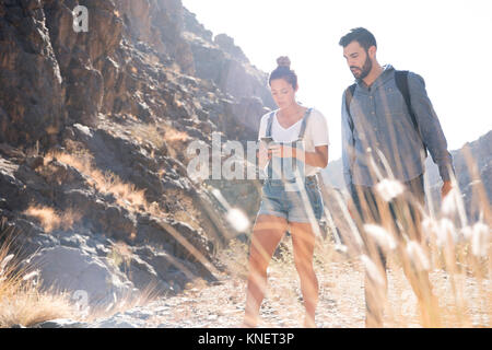 Les jeunes randonnées couple looking at smartphone pendant la randonnée dans la vallée, Las Palmas, Canaries, Espagne Banque D'Images