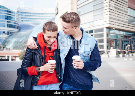 Jeune couple romantique avec du café à emporter à marcher ensemble dans la ville Banque D'Images