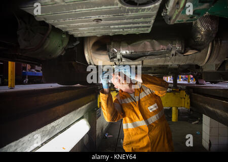 Un mécanicien travaillant sur le moteur d'un bus par le dessous, au dépôt de bus de Brighton et Hove Banque D'Images