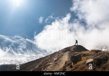 Jeune femme debout avec les armes sur le sommet de la montagne contre ciel bleu avec des nuages bas en plein jour. Paysage avec happy girl sur la colline, s Banque D'Images