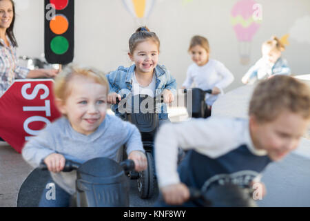 Les garçons et les filles à l'éducation préscolaire, course motos push in garden Banque D'Images