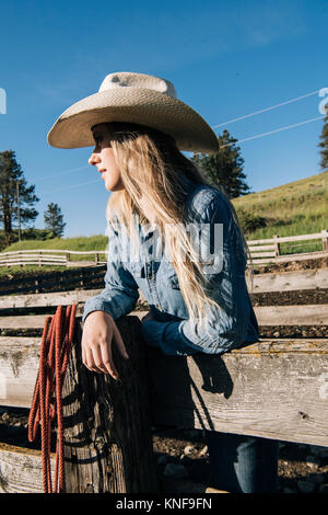 Cowgirl wearing cowboy hat leaning on fence, regardant ailleurs, Enterprise, Oregon, United States, Amérique du Nord Banque D'Images