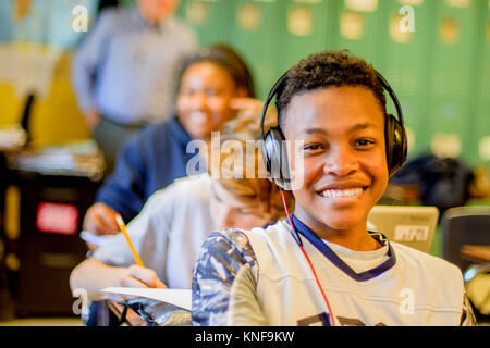 Portrait of teenage écolier portant des écouteurs au bureau de classe