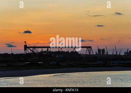 Vue panoramique sur les grues et port à conteneurs de Pointe-Noire pendant le coucher du soleil rouge Banque D'Images