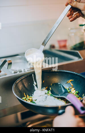 Chef cuisinier verse de la sauce à spaghetti dans une poêle. Restauration rapide le midi et restaurant bar Banque D'Images