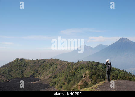 Un trekker se dresse sur les pentes du volcan Pacaya au Guatemala avec Agua et Fuego les volcans en arrière-plan Banque D'Images