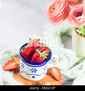 Une fraise mûre en émail mug sur planche de bois avec le textile. Printemps Été collation santé aux fruits Banque D'Images