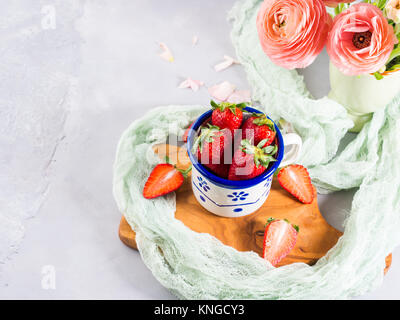 Une fraise mûre en émail mug sur planche de bois avec le textile. Printemps Été collation santé aux fruits Banque D'Images