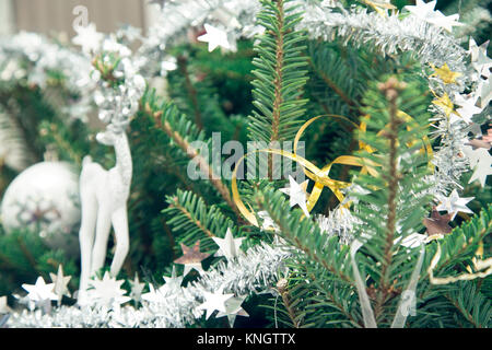 Un jouet et un renne blanc de guirlandes d'argent sur un sapin. Noël vert ou Nouvel An arrière-plan. Close up. Banque D'Images